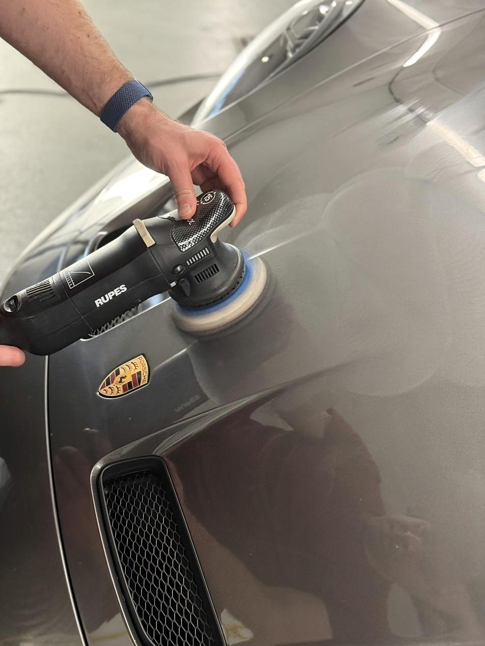 Maschinenpolitur auf der Haube eines silbernen Porsche