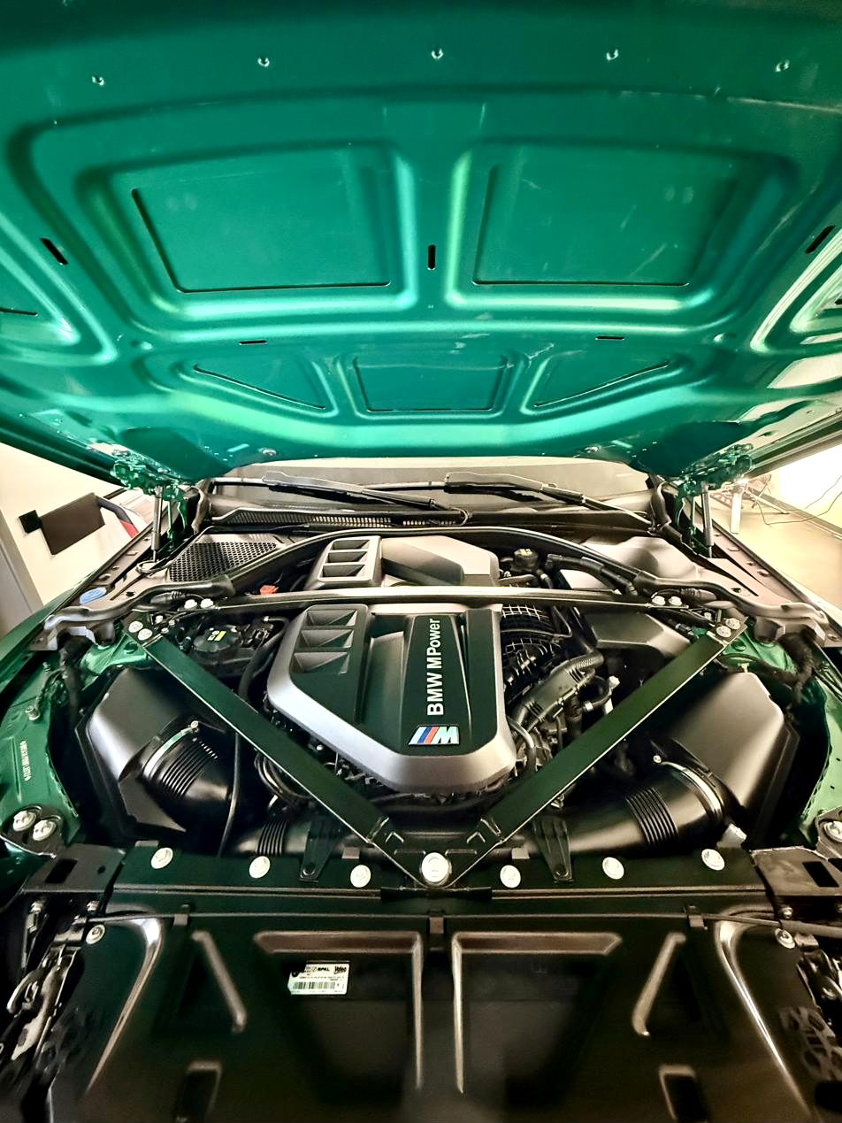 Geöffnete Motorhaube eines BMW M3 in Grün